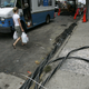 A woman walks past power lines on the sidewalk as workers try to restore electrical service July 23, 2006 in the Queens borough of New York City.